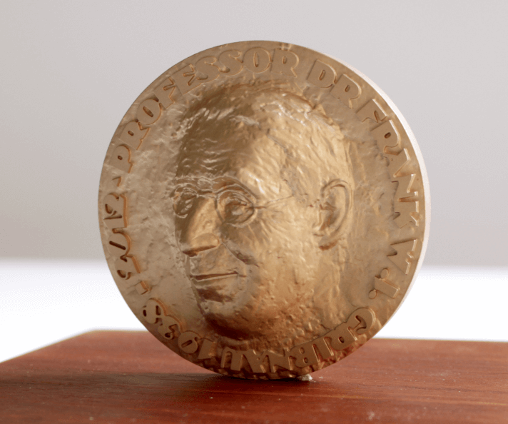 Voorkant van een messing penning op een houten tafel